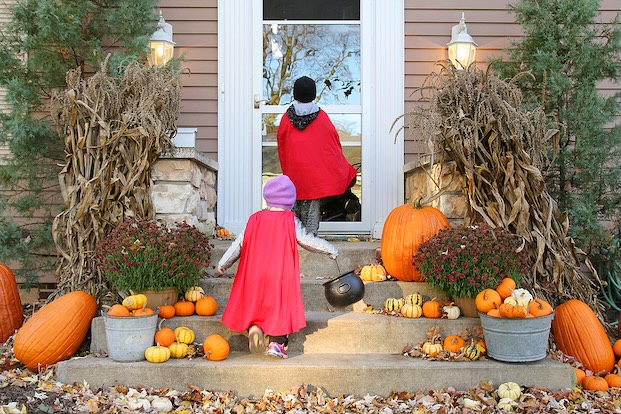 Kids trick or treating in front of a house.